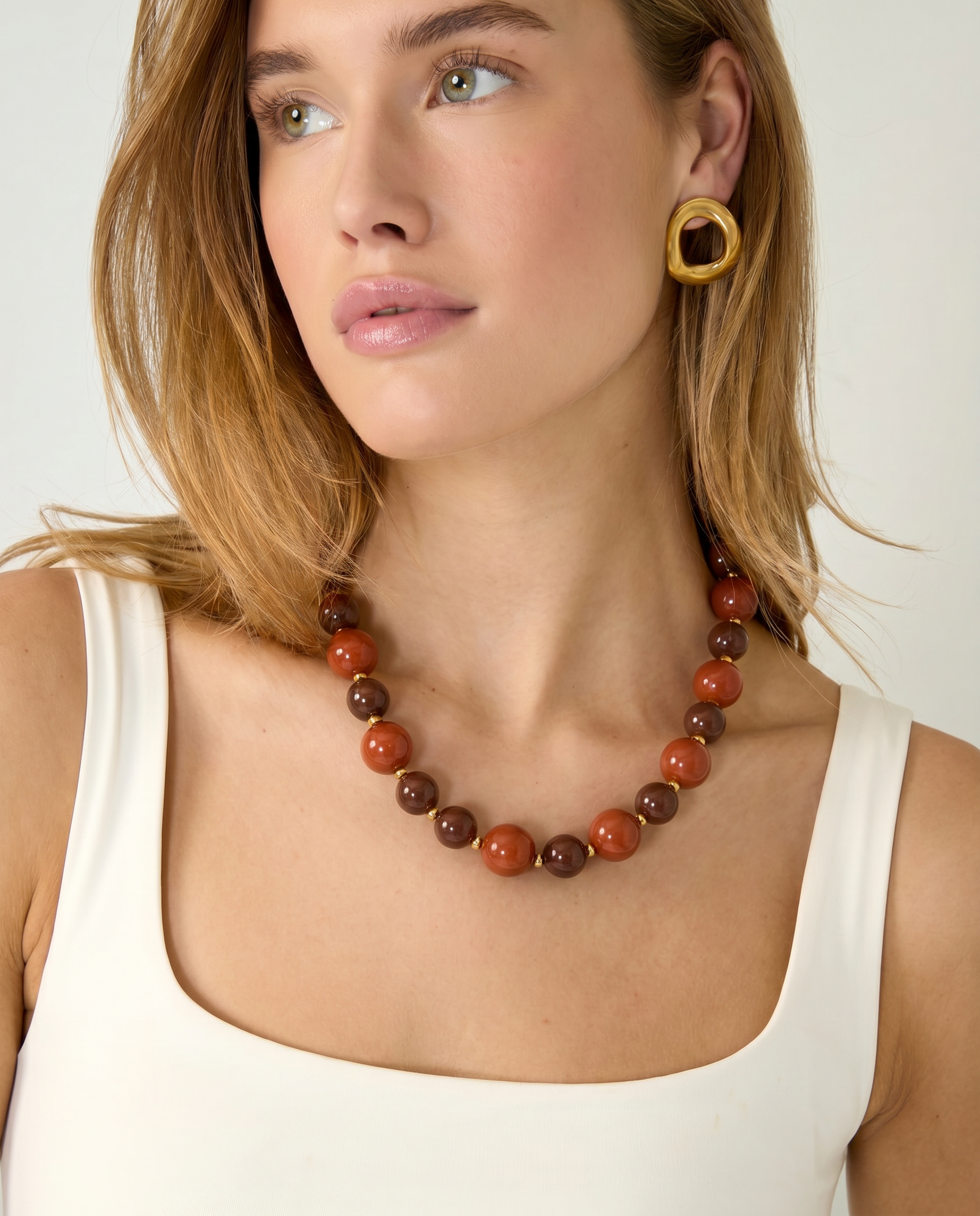 Collar de bolas acrílicas en tonos tierra combinado con un look neutro.