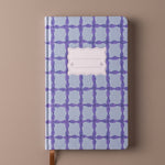Cuaderno premium de tapa dura con estampado azul y marcapáginas de cinta.