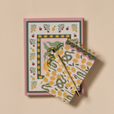 Cuaderno de notas rosa con ilustraciones de serpientes verdes y frutas, acompañado de un bloc de notas a juego con estampado de limones.
