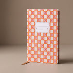 Cuaderno de tapa dura Orange Check Tulip con estampado geométrico en tonos naranja y blanco.