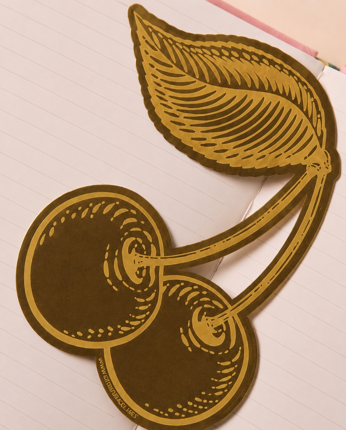 Detalle del marcapáginas de metal con forma de cerezas.