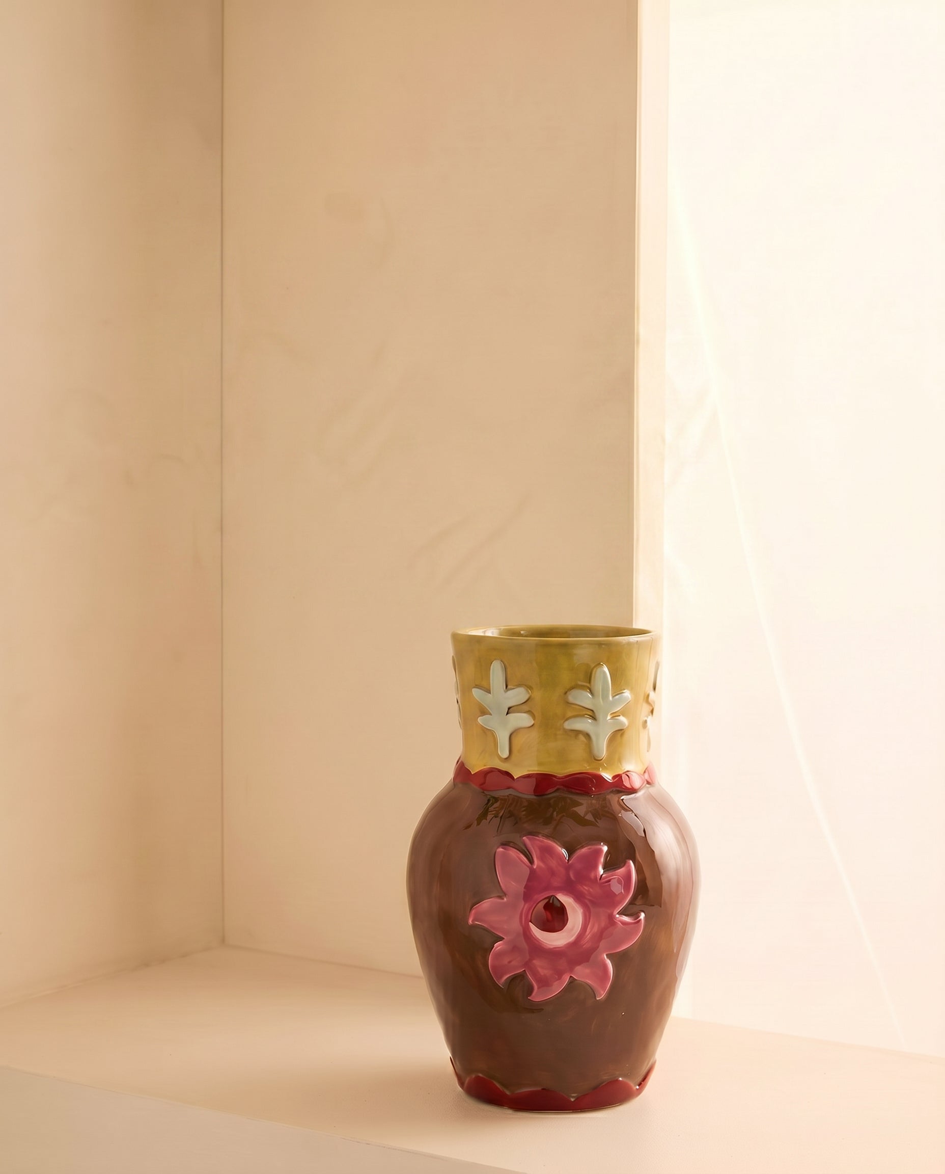 Jarrón de cerámica con diseño floral utilizado como florero con flores naturales.
