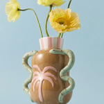 Jarrón decorativo de cerámica con flores amarillas sobre fondo azul.