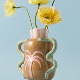 Jarrón decorativo de cerámica con flores amarillas sobre fondo azul.