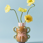 Jarrón de cerámica con palmera en relieve y serpientes, con flores amarillas.