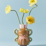 Jarrón de cerámica con palmera en relieve y serpientes, con flores amarillas.