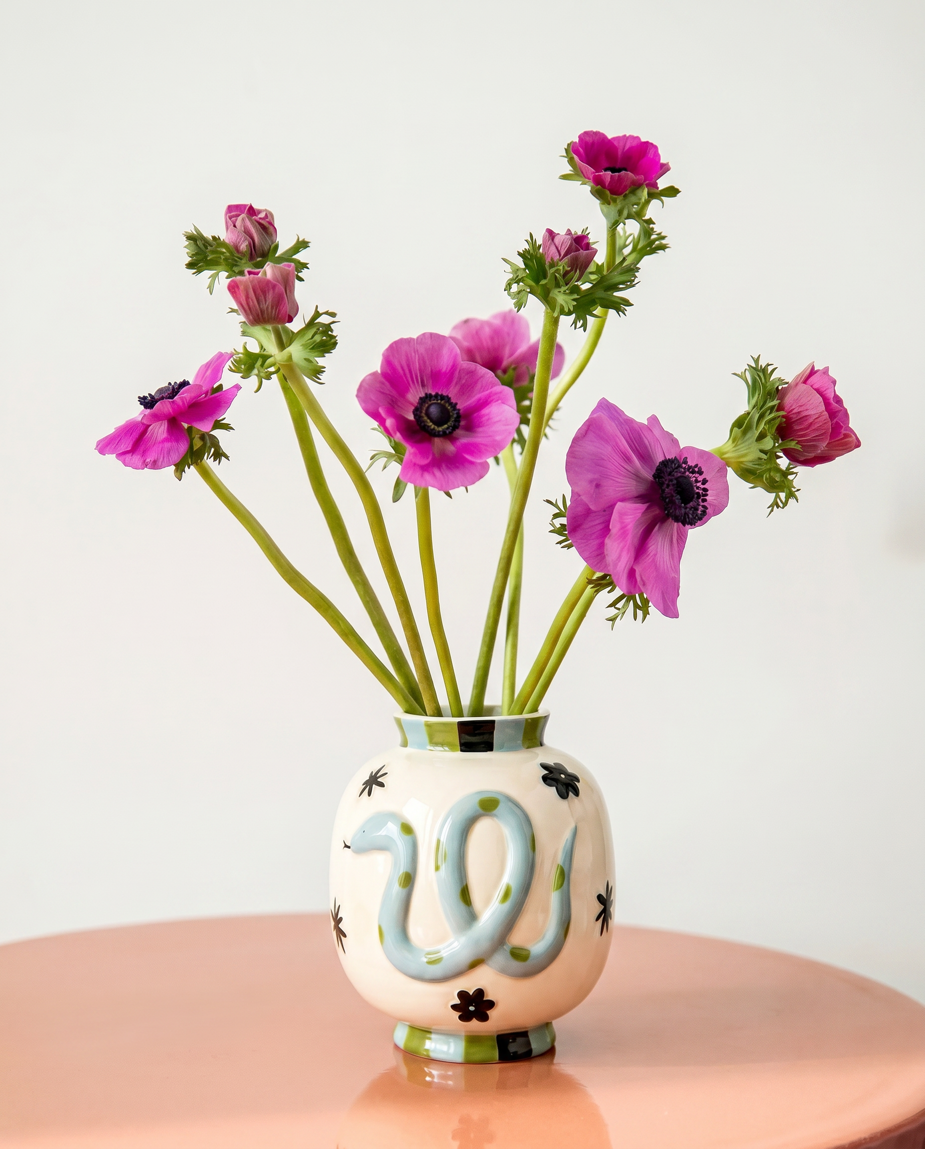 Jarrón de cerámica con serpiente azul y flores rosas.