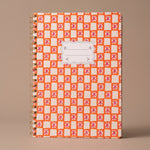 Libreta A4 de espiral Orange Check con estampado geométrico en tonos naranja y blanco.