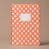 Libreta A4 de espiral Orange Check con estampado geométrico en tonos naranja y blanco.