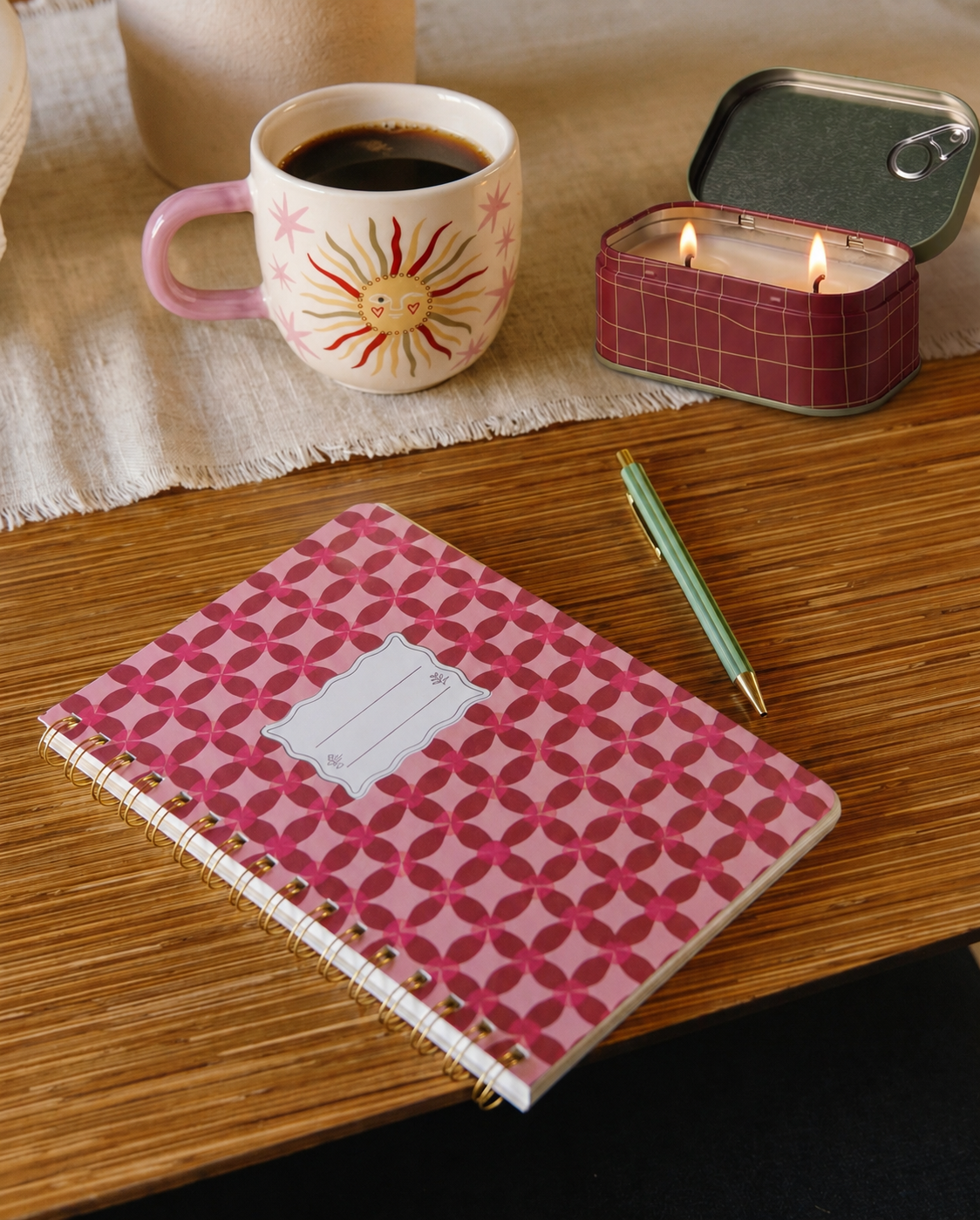 Libreta Pinwheel Pink sobre un escritorio junto a una taza de café y accesorios de papelería.