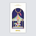 Llavero esmaltado con diseño de carrusel en tonos pastel y detalles dorados.