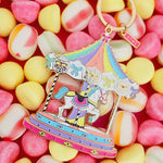 Llavero carrusel pastel de All The Ways To Say sobre fondo de caramelos de colores.