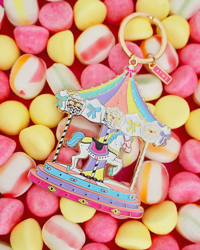 Llavero carrusel pastel de All The Ways To Say sobre fondo de caramelos de colores.
