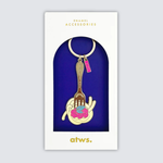 Detalle del llavero dorado con ilustración de espaguetis y salsa rosa.