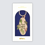 Llavero esmaltado dorado con diseño de hojas verdes y texto Plant Addict Club.