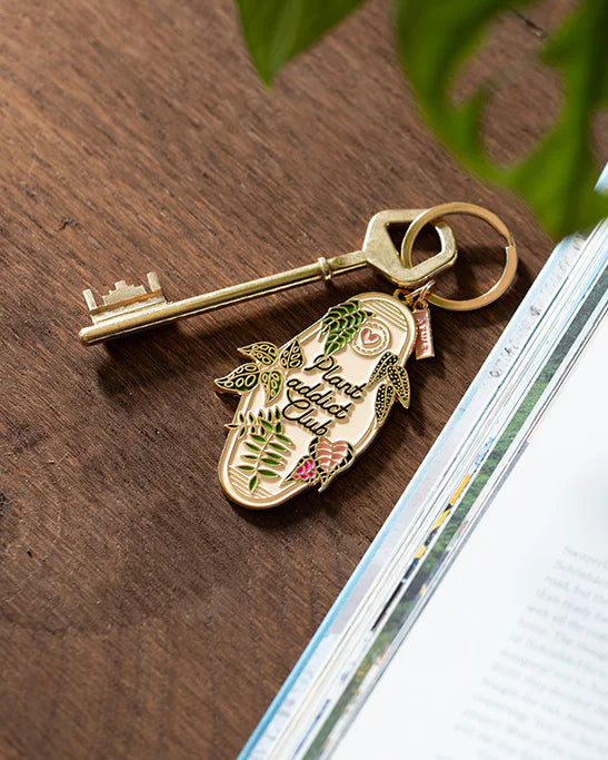 Llavero Plant Addict Club de All The Ways To Say junto a una llave dorada.