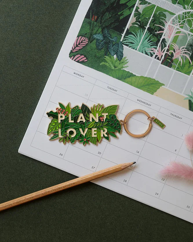 Llavero esmaltado con hojas verdes y letras Plant Lover en dorado.
