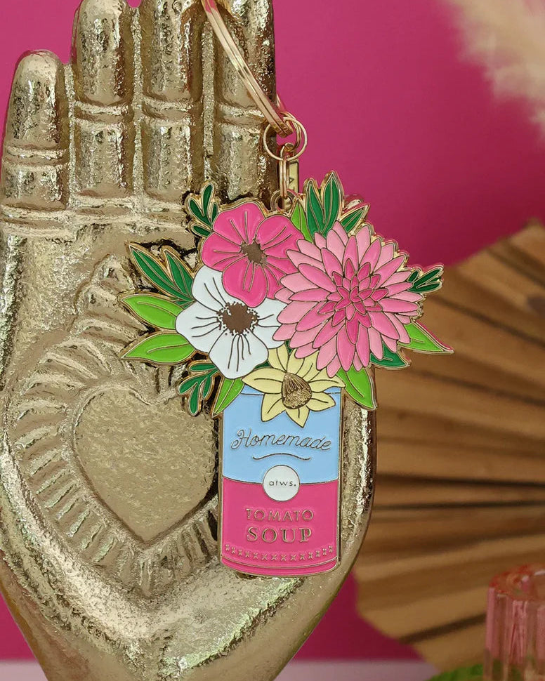 Llavero ramo floral de All The Ways To Say colgado en mano dorada decorativa.