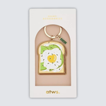 Llavero esmaltado con diseño de tostada con aguacate y huevo frito.