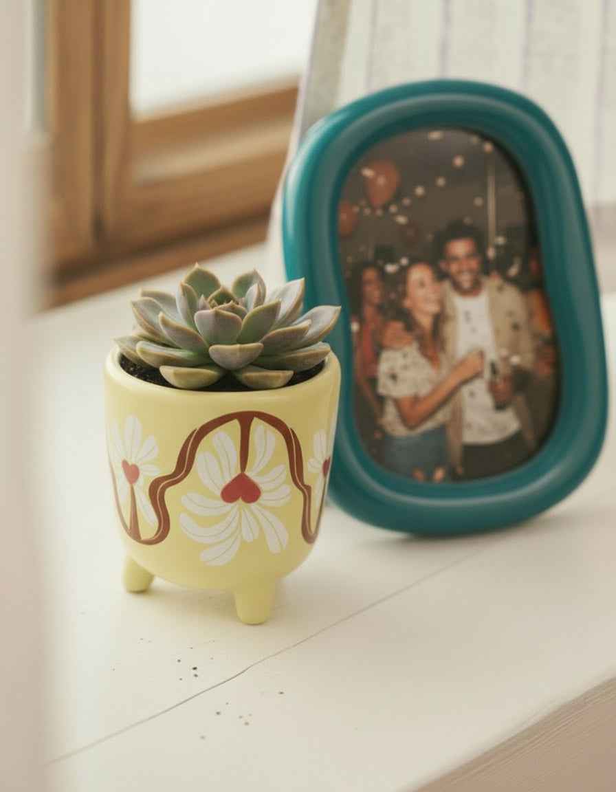 “Detalle del diseño floral rojo y blanco en la maceta de cerámica amarilla.