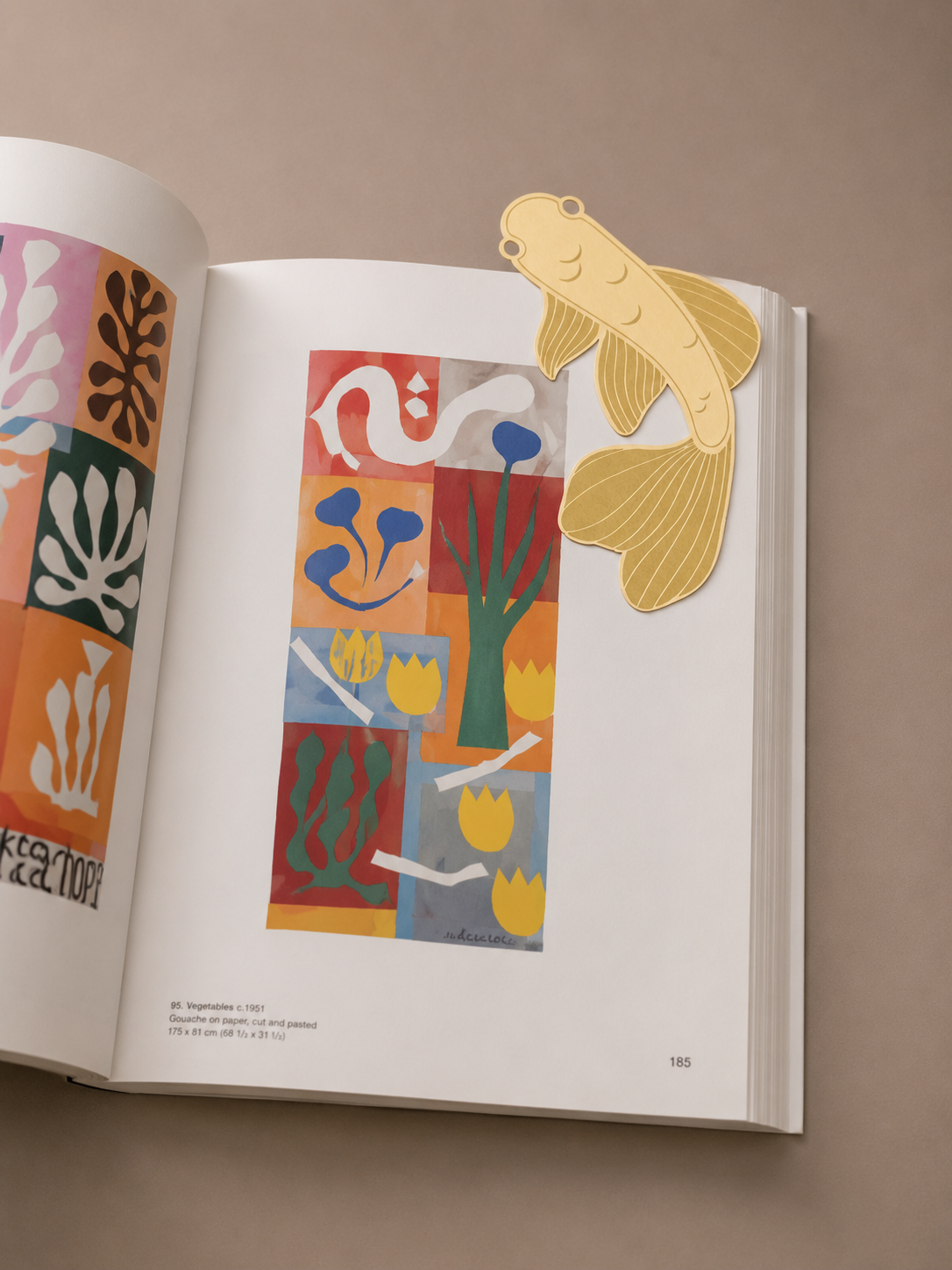 Marcapáginas de metal con diseño de pez koi marcando una página de un libro abierto.