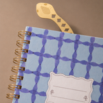 Marcapáginas de metal con diseño de serpiente sobresaliendo de un cuaderno.
