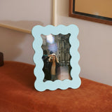 Marco de fotos azul de MDF en una escena decorativa junto a pared y cuadro