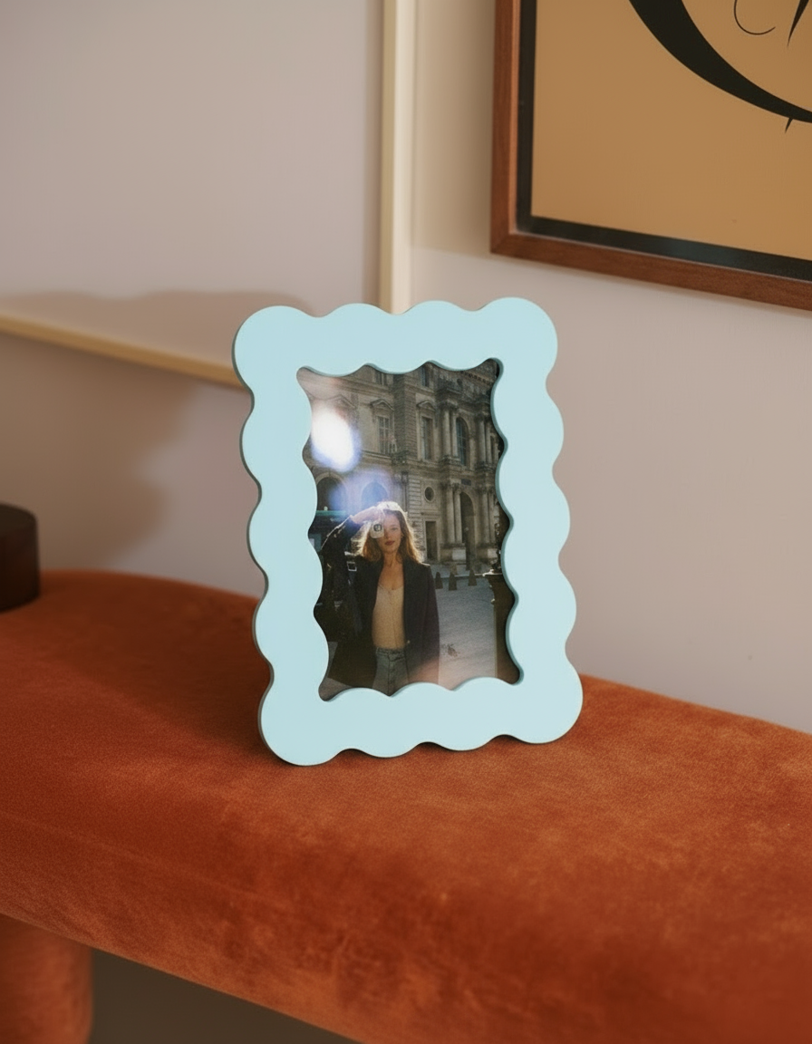 Marco de fotos azul de MDF con borde ondulado, colocado sobre un banco tapizado en terciopelo