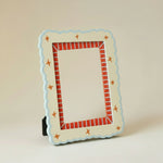 Marco de fotos decorativo de MDF en tonos crema y azul con borde rojo, vista frontal.