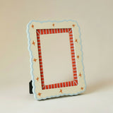 Marco de fotos decorativo de MDF en tonos crema y azul con borde rojo, vista frontal.