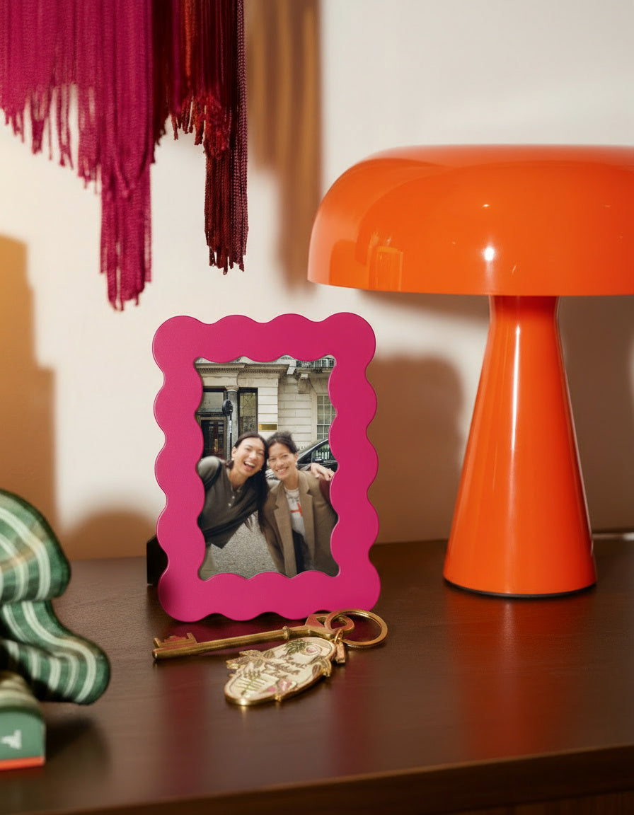 Marco de fotos rosa de MDF con borde ondulado, vista frontal sobre superficie de madera