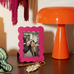 Marco de fotos rosa de MDF con borde ondulado, vista frontal sobre superficie de madera