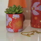 Detalle del mini macetero de cerámica con estampado celestial en tonos rojos y lilas.