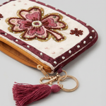 Primer plano de monedero con flor rosa bordada, cuentas decorativas y detalles brillantes.