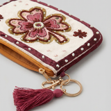 Primer plano de monedero con flor rosa bordada, cuentas decorativas y detalles brillantes.