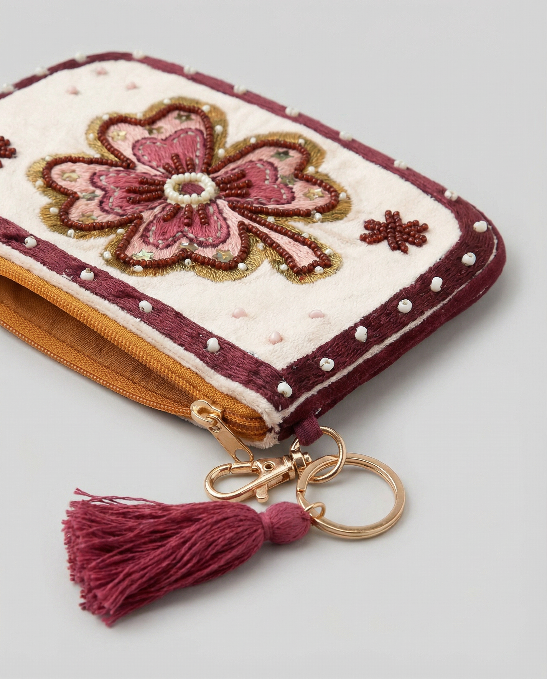 Primer plano de monedero con flor rosa bordada, cuentas decorativas y detalles brillantes.