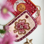 Monedero floral bordado en tonos rosa, crema y granate con abalorios, junto a otro monedero decorativo.