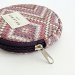 Monedero redondo de jacquard con estampado de espiga en tonos rosa, lila y beige.
