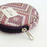 Monedero redondo de jacquard con estampado de espiga en tonos rosa, lila y beige.