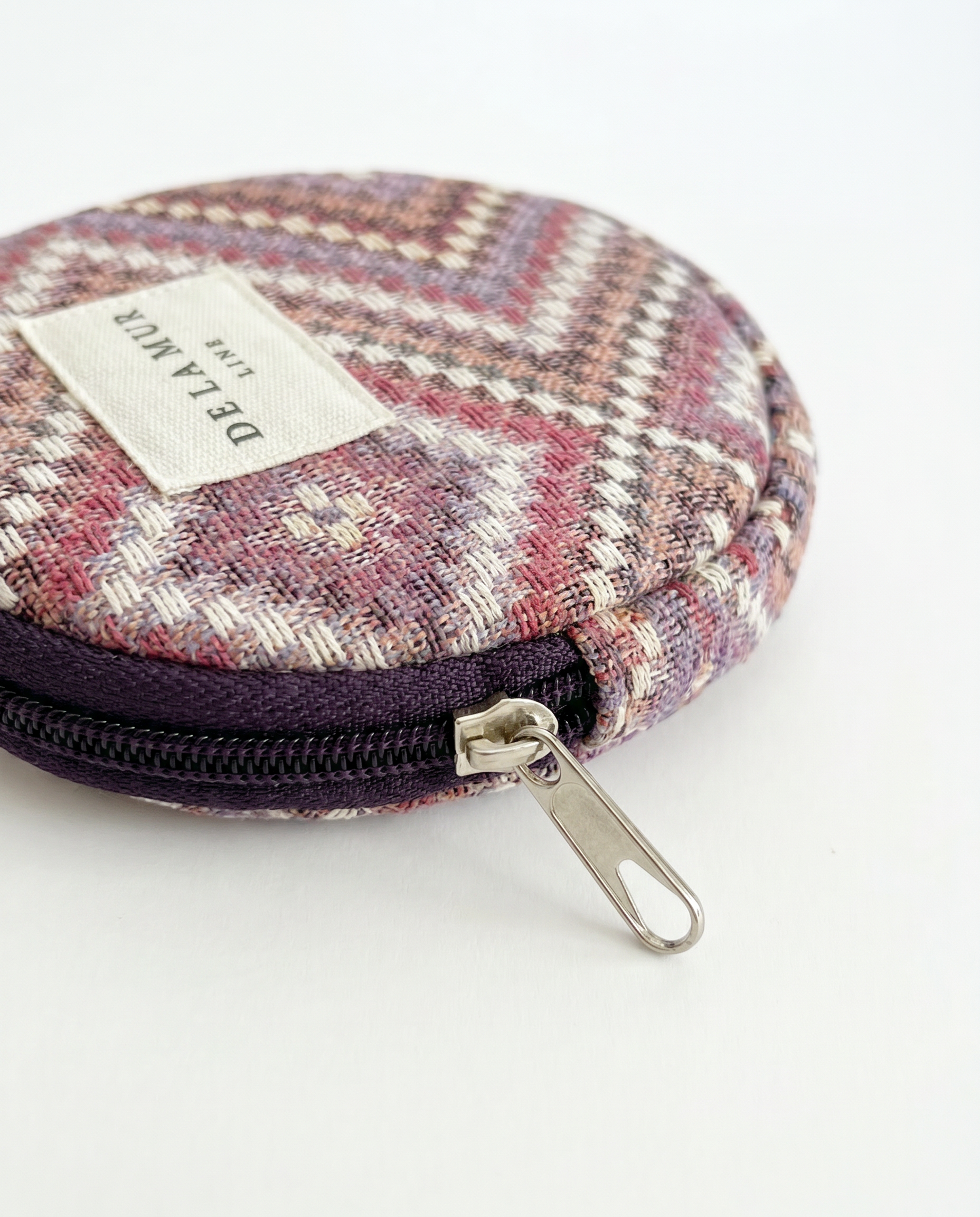 Monedero redondo de jacquard con estampado de espiga en tonos rosa, lila y beige.