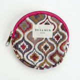 Monedero redondo de jacquard con estampado geométrico en tonos rosa, lila y beige.