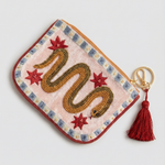 Monedero crema con serpiente dorada bordada, estrellas rojas y borla granate, vista diagonal.