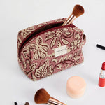 Neceser de jacquard con estampado floral en tonos rosa y granate, vista frontal.