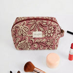Neceser de jacquard floral con brochas y productos de maquillaje alrededor.