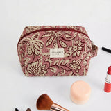 Neceser de jacquard floral con brochas y productos de maquillaje alrededor.