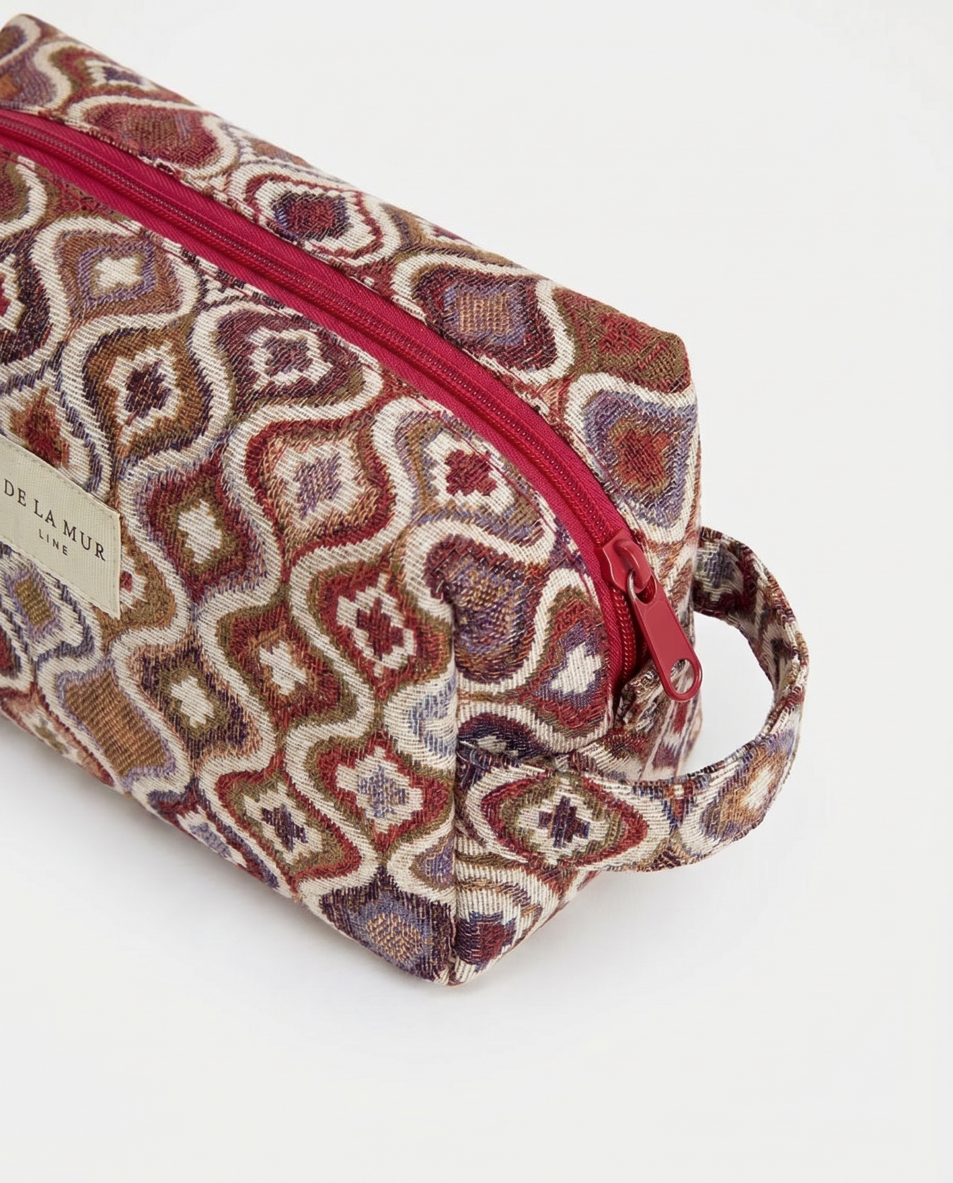 Neceser de jacquard con cremallera superior y estampado geométrico visto en perspectiva.