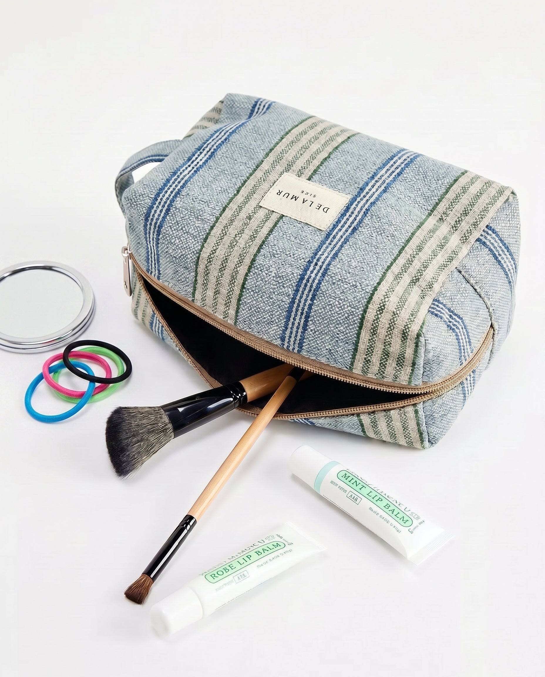 Neceser de jacquard de rayas azules con productos de maquillaje alrededor.