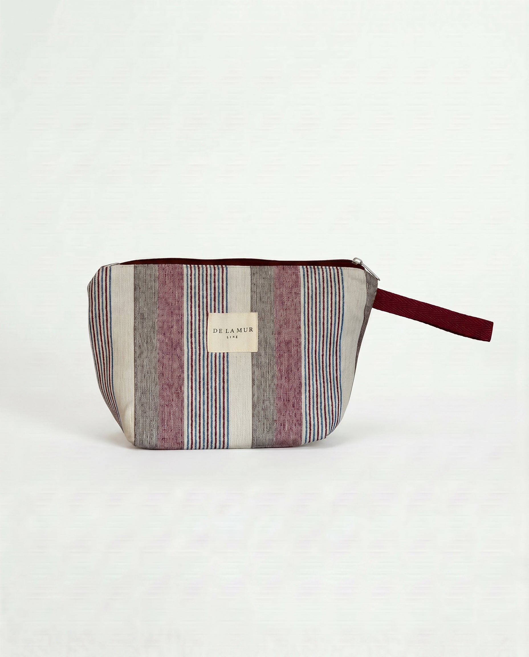 Neceser de jacquard con rayas en tonos granate, azul y crudo, vista frontal.