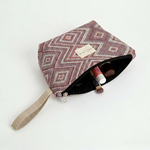 Neceser de jacquard abierto mostrando su interior y asa lateral beige.