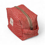 Neceser rectangular con cremallera beige y asa lateral, tejido rayado.

